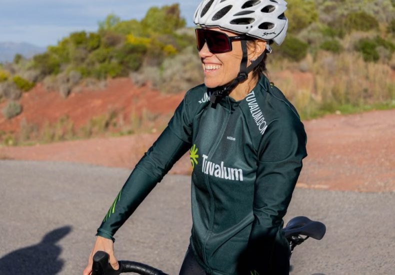 A woman cyclist enjoying a ride on a sunny day, wearing sports gear and helmet.