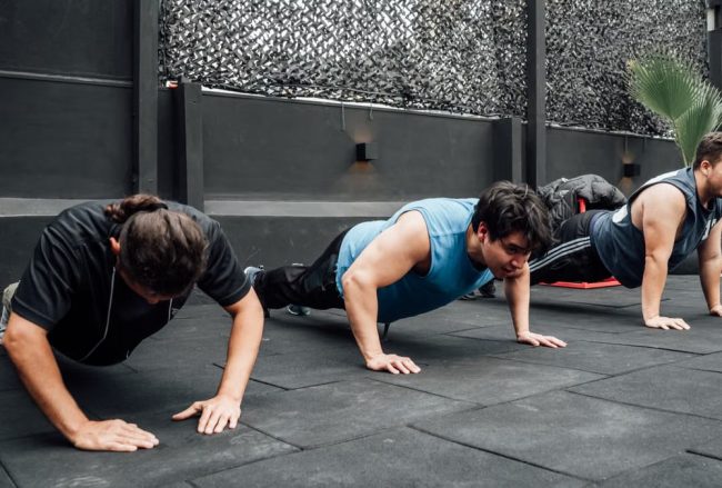 Men performing push-ups during a group workout session in Mexico City gym.